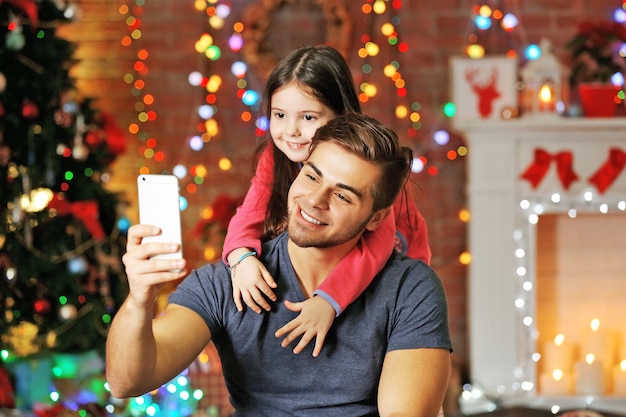 Il fratello maggiore e la sorellina si fotografano con uno smartphone nel soggiorno di Natale