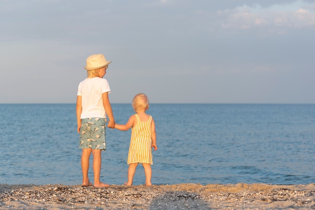 Il fratello maggiore tiene la sorellina per mano e guarda il mare