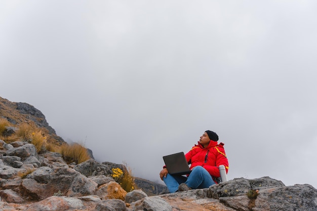 Il freelance dei Millennials lavora da remoto durante un viaggio in montagna. Caffè mattutino al lavoro al computer. Concetto di lavoro in vacanza