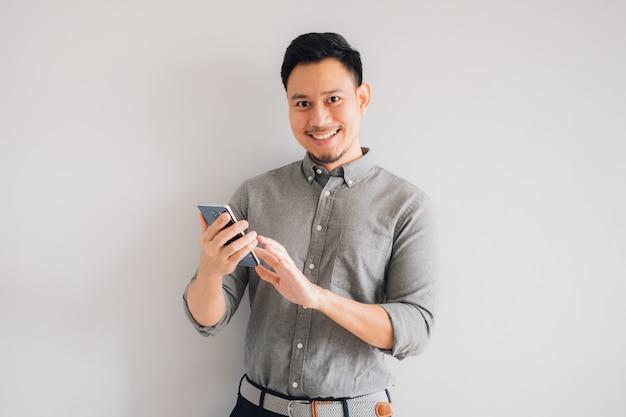 Il fronte felice di sorriso dell&#39;uomo asiatico bello utilizza lo smartphone