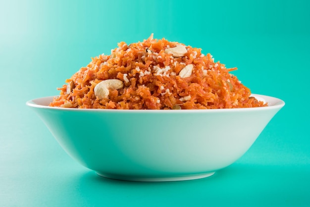 Il Gajar Halwa è un budino dolce a base di carote proveniente dall'India. Guarnito con anacardi, mandorle e servito in una ciotola su uno sfondo di legno colorato