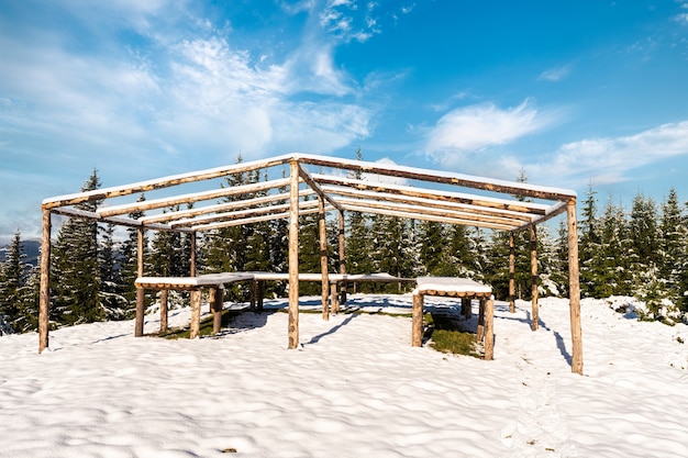 Il gazebo in cima alla montagna si trova in un prato innevato, bagnato dalla luce del sole freddo brillante