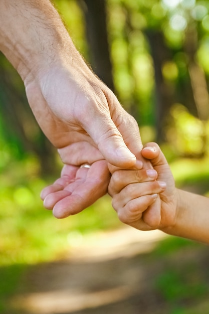 Il genitore che tiene la mano del bambino con una superficie felice