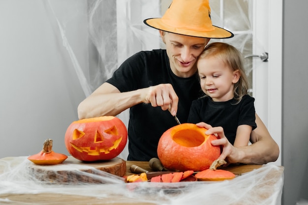 Il genitore con il bambino sta intagliando la zucca per halloween