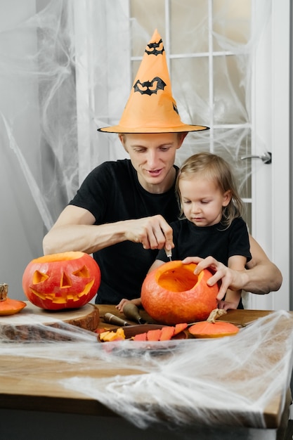 Il genitore con il bambino sta intagliando la zucca per halloween