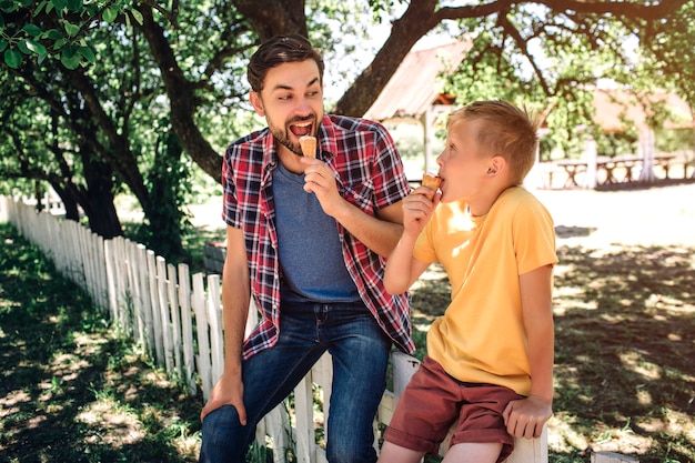 Il genitore felice ed eccitato sta guardando suo figlio e sta mangiando il gelato