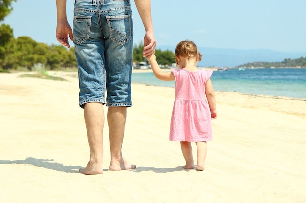 Il genitore tiene la mano di un bambino piccolo in mare