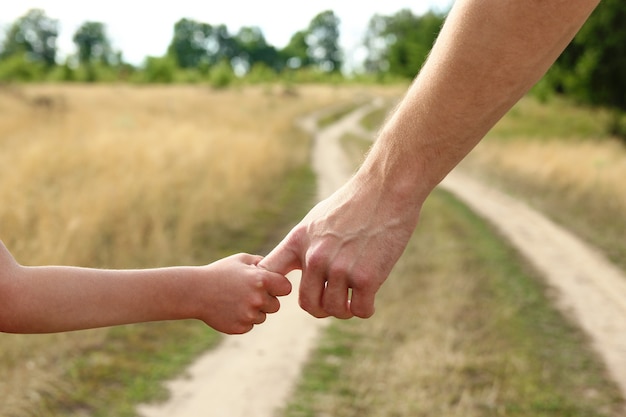 Il genitore tiene la mano di un bambino piccolo vicino alla strada