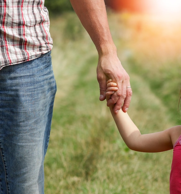 il genitore tiene la mano di un bambino sulla natura