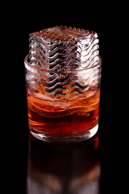 Il ghiaccio decorato è troppo grande per un bicchiere di Negroni rosso arancione.