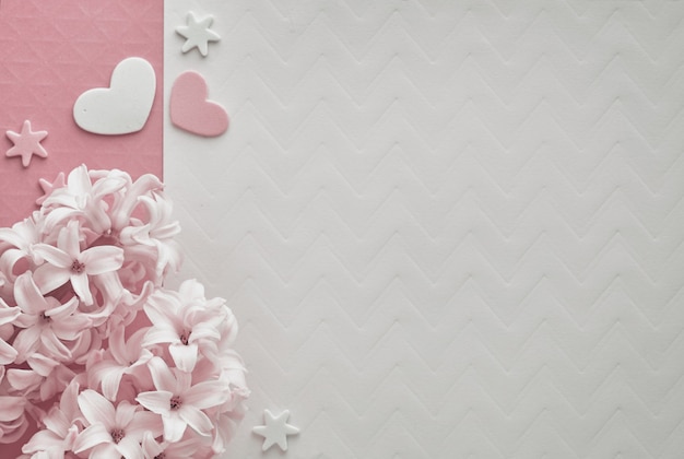 Il giacinto rosa della perla fiorisce su fondo colorato con i cuori decorativi, copia-spazio