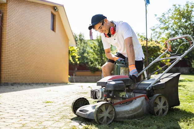 Il giardiniere con la tanica di benzina svita il tappo del carburante del tosaerba