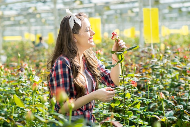 Il giardiniere della ragazza o il lavoratore della serra si prende cura dei fiori nella serra