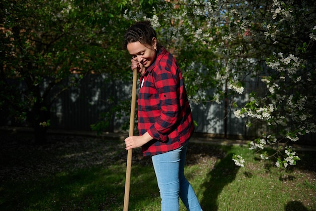 Il giardiniere femminile carino fa un tuffo nel giardino con alberi da frutto all'inizio della primavera