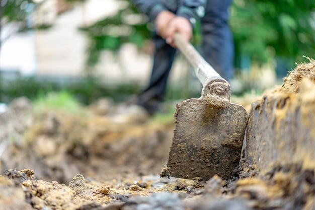 Il giardiniere scava il terreno con la sua attrezzatura per il giardinaggio e prepara il terreno per la piantagione