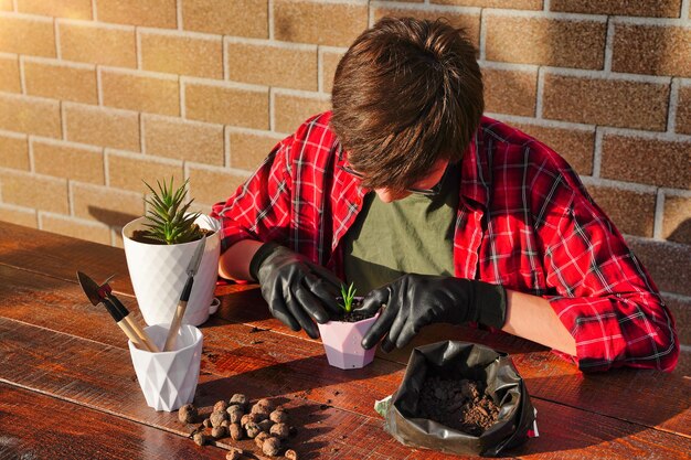 Il giardiniere trapianta i fiori in un nuovo vaso Strumento per piantare terreno e drenaggio