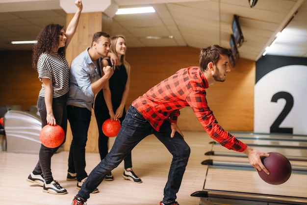 Il giocatore di bocce maschio lancia la palla, lanciando in azione