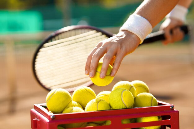 Il giocatore di tennis prende una palla da un canestro