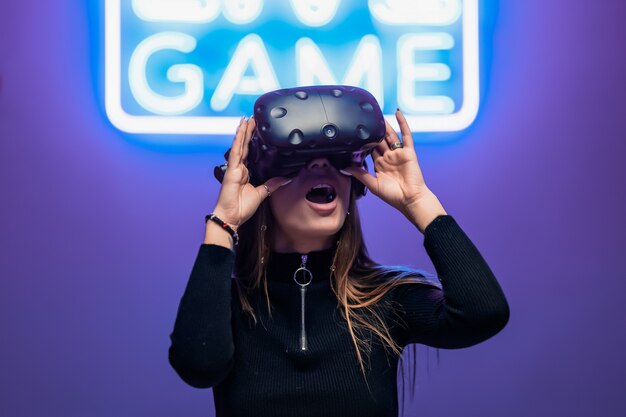 Il giocatore è sorpreso durante il gioco VR. Gioco di insegne al neon.