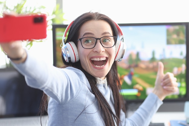 Il giocatore gioioso della donna gira video sullo smartphone sullo sfondo del gioco per computer Esport femminili