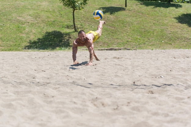 Il giocatore maschio del gioco di beach volley salta sulla sabbia