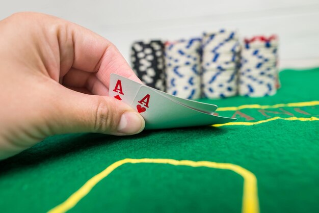 Il giocatore mostra due assi di carte da gioco su un tavolo verde in un casinò con fiches da gioco