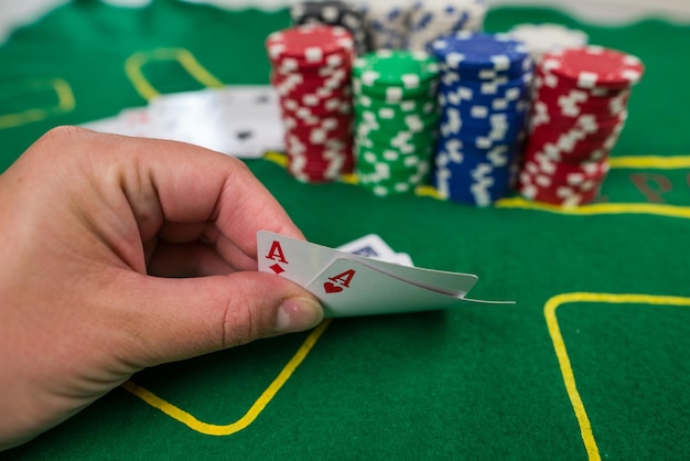 Il giocatore mostra gli assi delle carte da gioco su un tavolo verde in un casinò con fiches da gioco