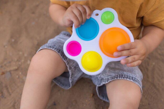 Il giocattolo sensoriale antistress colorato e alla moda si agita spingendolo pop e semplice fossetta nelle mani dei bambini i bambini condividono giocattoli e giocano insieme