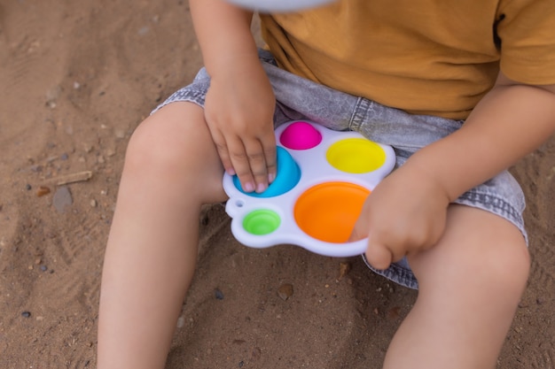 Il giocattolo sensoriale antistress colorato e alla moda si agita spingendolo pop e semplice fossetta nelle mani dei bambini i bambini condividono giocattoli e giocano insieme