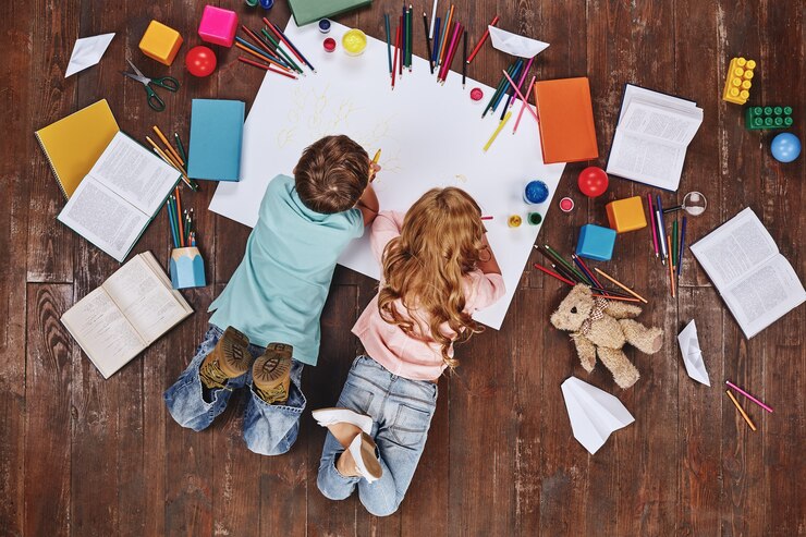 Il gioco è il lavoro dei bambini dell'infanzia sdraiati vicino a libri e giocattoli mentre disegnano