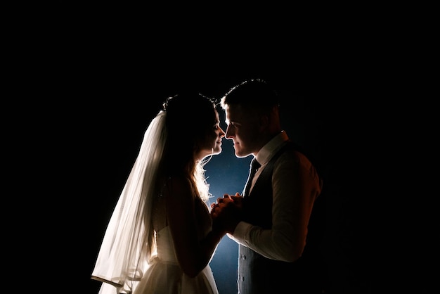 Il giorno del matrimonio degli sposi notturni giura vicino all'arco con luci sullo sfondo dei fuochi d'artificio