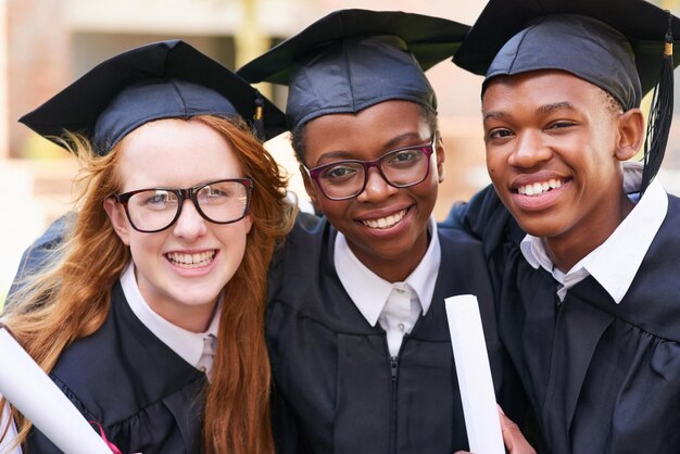 Il giorno della laurea è tutto su di noi Ritratto di un felice gruppo di studenti in piedi fuori il giorno della laurea