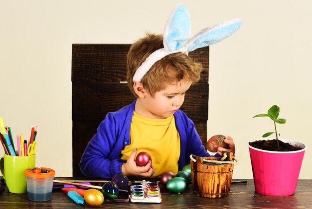 Il giorno di Pasqua il bambino sveglio che dipinge l'uovo che celebra le feste con la creatività di Pasqua dei bambini dei bambini