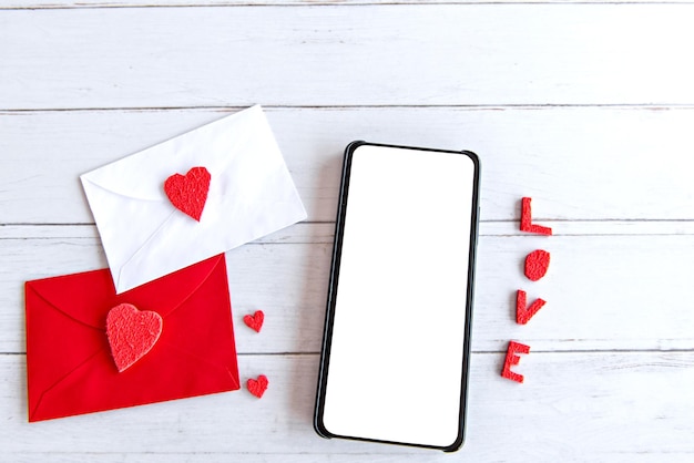 Il giorno di San Valentino concetto lettera d'amore e cellulare con schermo bianco sul tavolo di legno