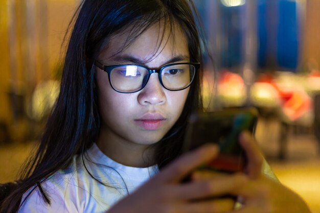 Il giovane adolescente femminile asiatico gode di di usando il suo telefono