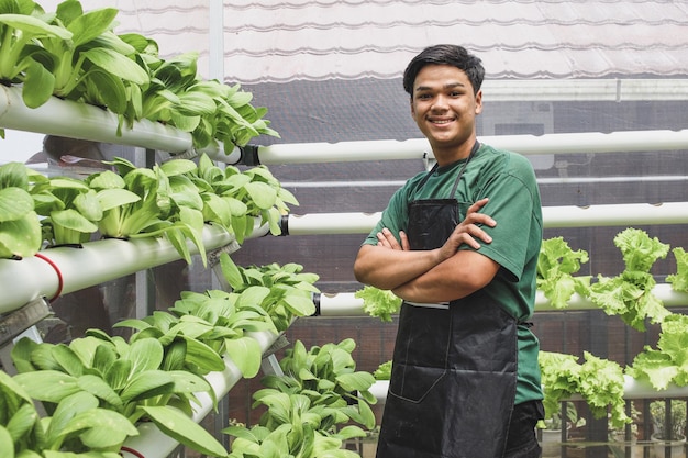 Il giovane agricoltore di successo sorride con sicurezza intorno all'idroponica delle verdure in serra