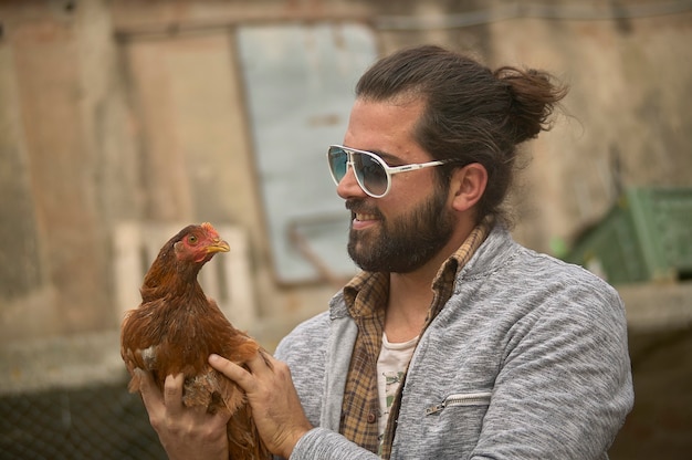 Il giovane agricoltore tiene in mano un pollo vivo