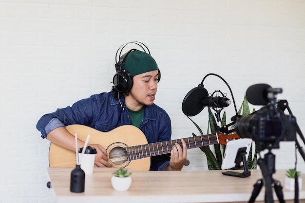Il giovane asiatico in stile casual canta e suona la chitarra sul podcast musicale