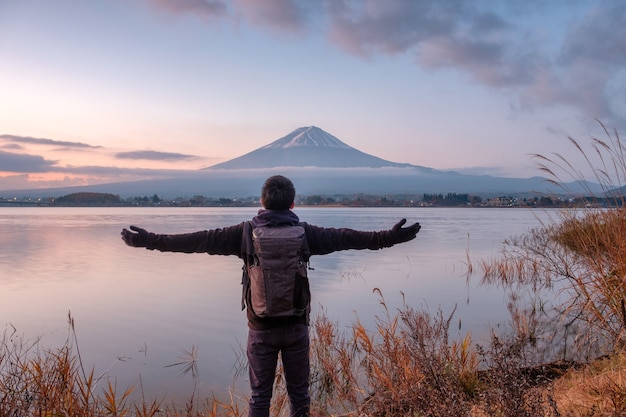 Il giovane asiatico sta guardando il Monte Fuji sul lago Kawaguchiko al mattino