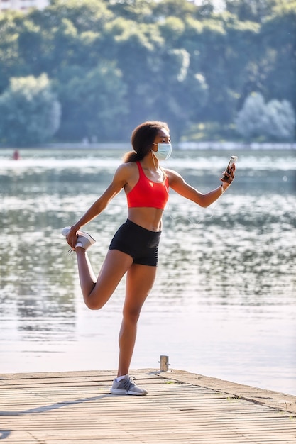 Il giovane atleta femminile nero conduce una sessione di allenamento al mattino su un molo vicino al lago