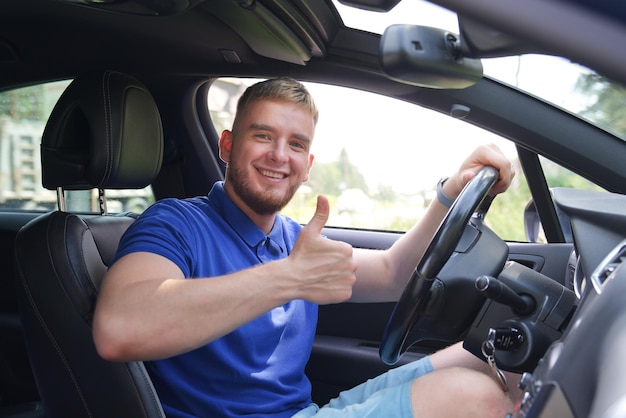 Il giovane autista felice che guida la sua auto guarda la strada che non indossa una cintura di sicurezza concetto di non sicuro