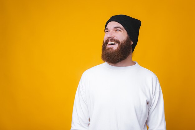 Il giovane barbuto sta distogliendo lo sguardo e sorridendo sul fondo giallo.