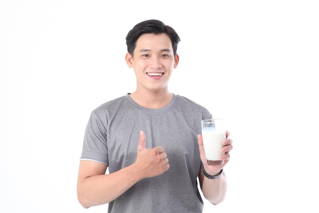 Il giovane bello e allegro sportivo asiatico tiene un bicchiere di latte fresco isolato su priorità bassa