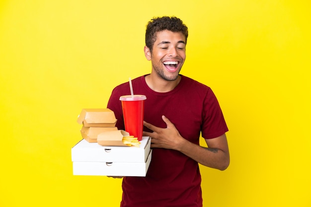 Il giovane brasiliano che tiene le pizze e gli hamburger ha isolato il fondo che sorride molto