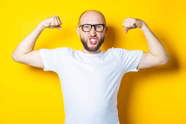 Il giovane calvo con la barba mostra i muscoli