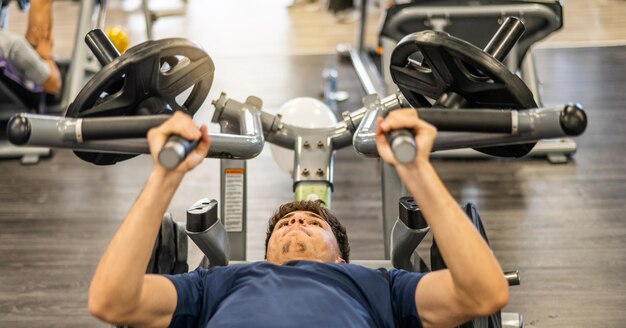 Il giovane che allena il suo corpo in palestra è in una macchina per i pesi