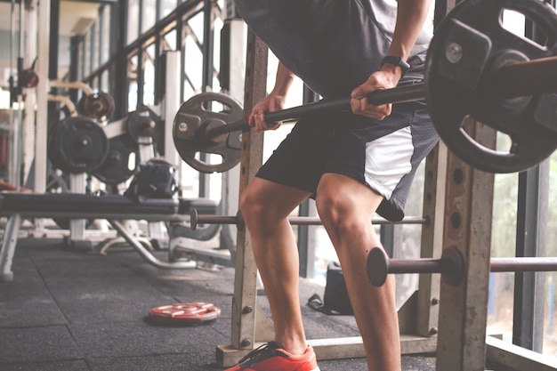 Il giovane che il principiante si allena con il bilanciere in palestra