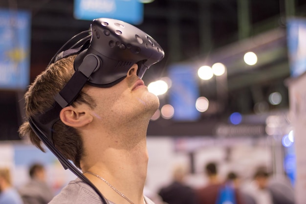 Il giovane che indossa occhiali per realtà virtuale in una fiera si sta divertendo