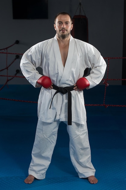 Il giovane che pratica il suo karate muove la cintura nera del kimono bianco