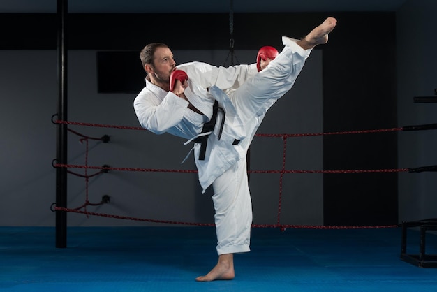 Il giovane che pratica il suo karate muove la cintura nera del kimono bianco